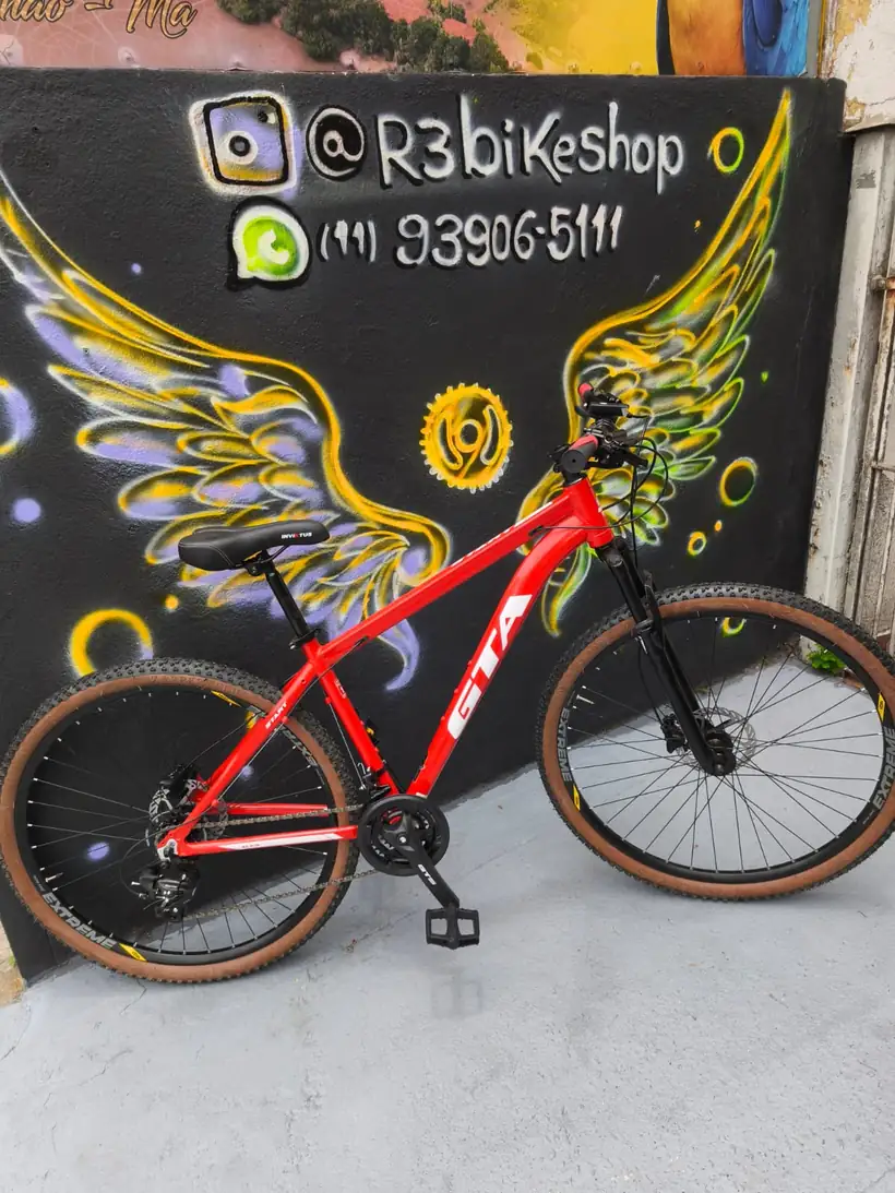 Bicicleta vermelha diante do mural de asas da R3 Bike Shop