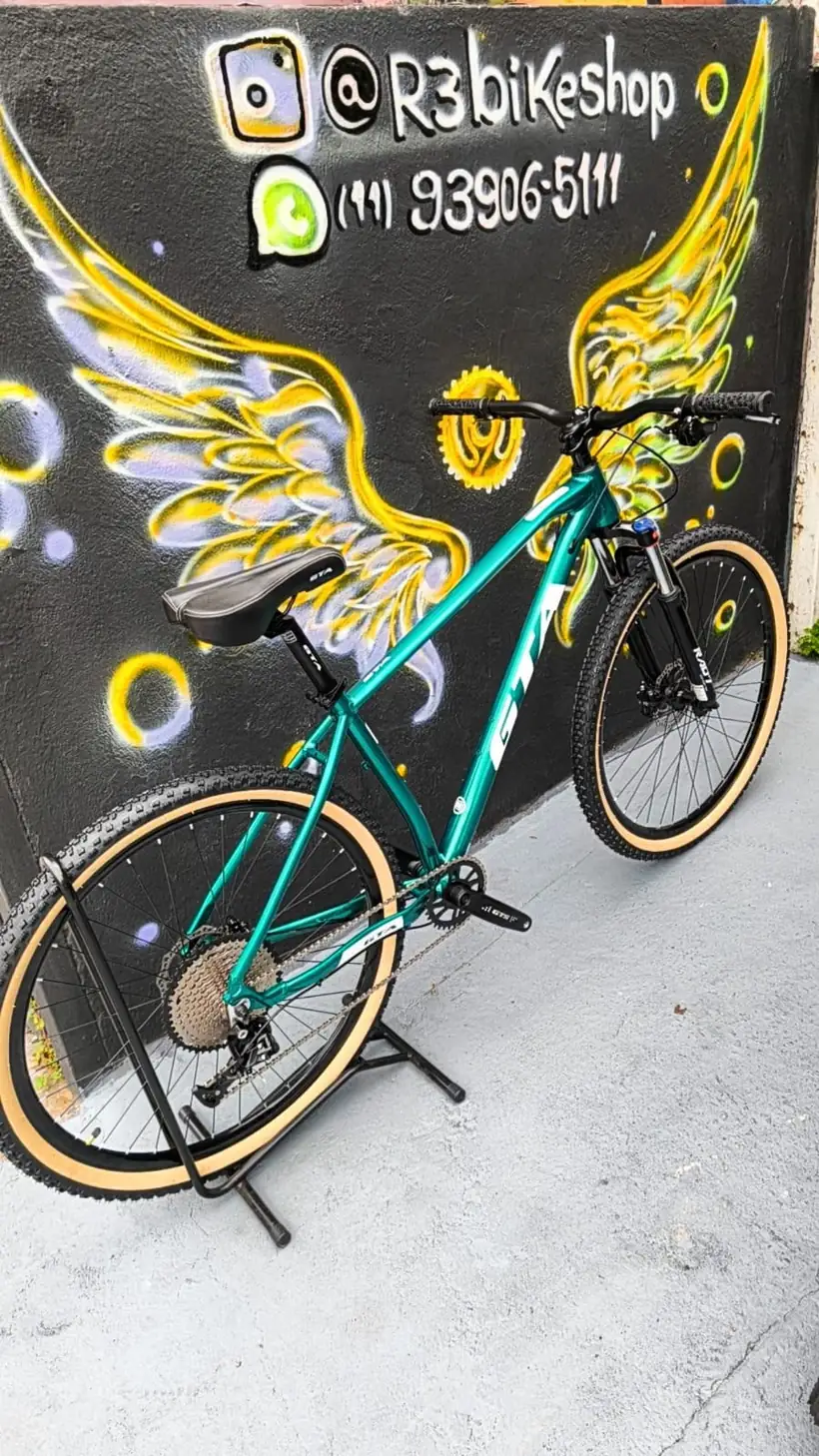 Bicicleta azul turquesa diante do mural de asas da R3 Bike Shop